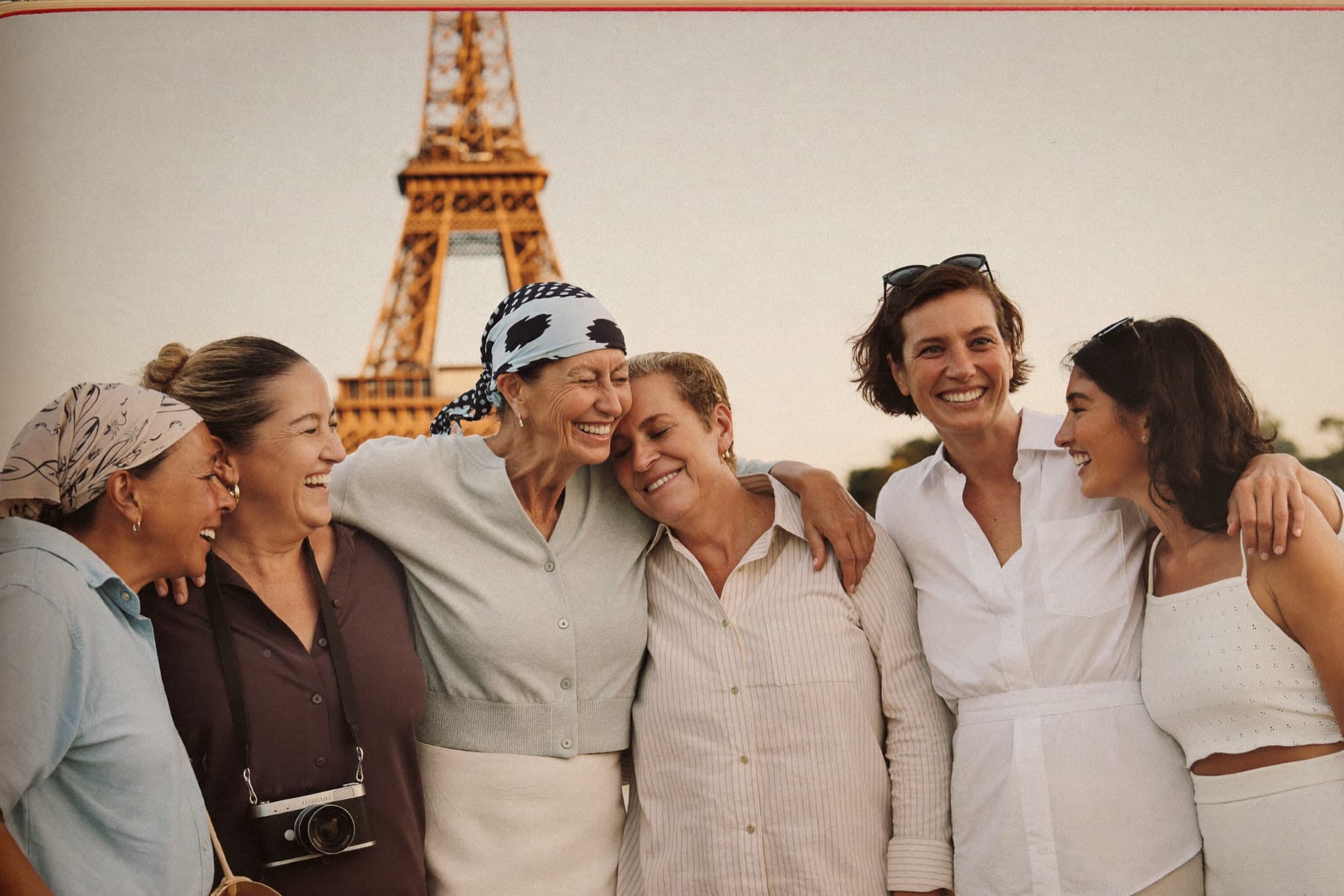 Un grupo de mujeres riéndose juntas con la Torre Eiffel detrás